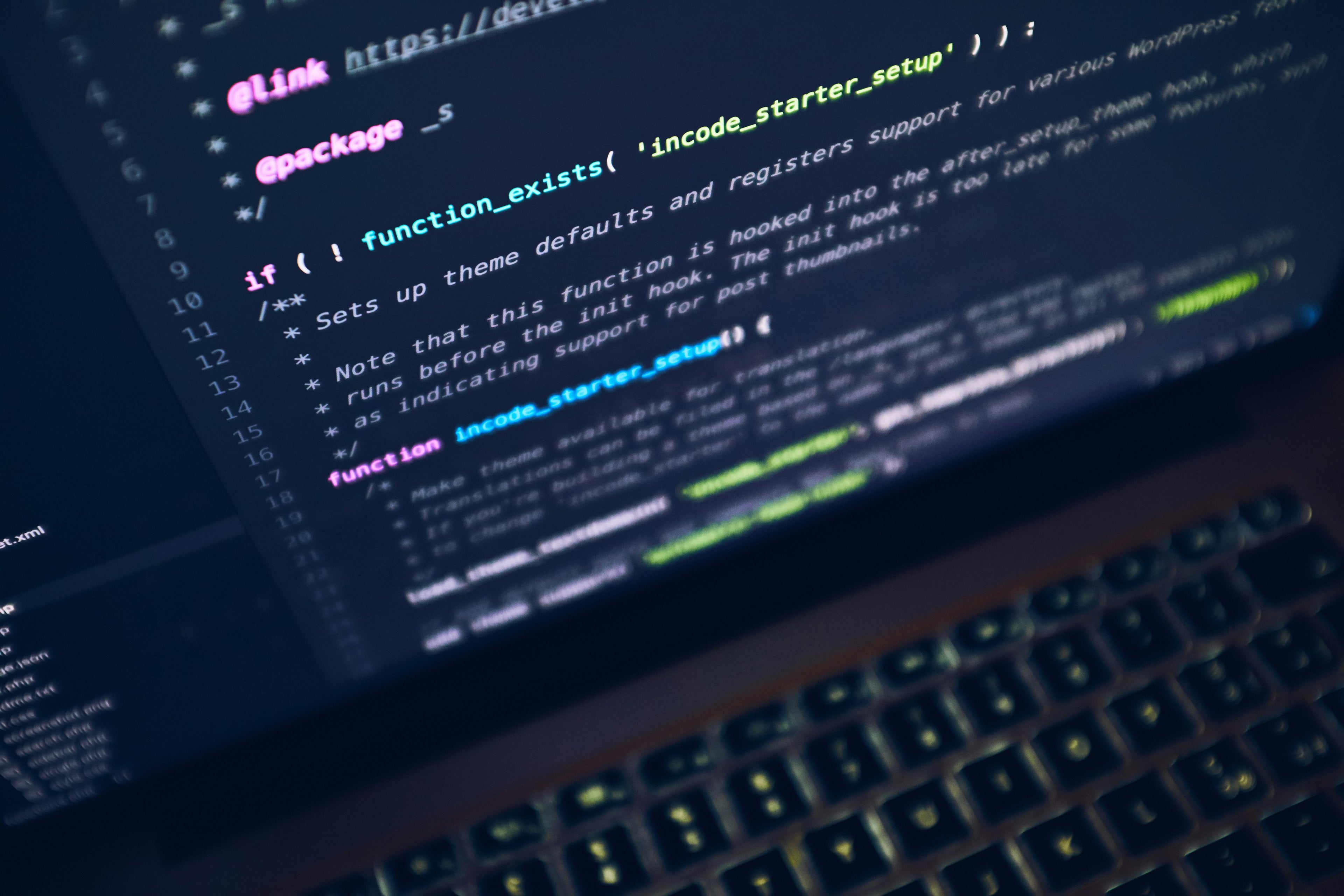 Close-up of a laptop screen displaying colorful code lines on a dark background